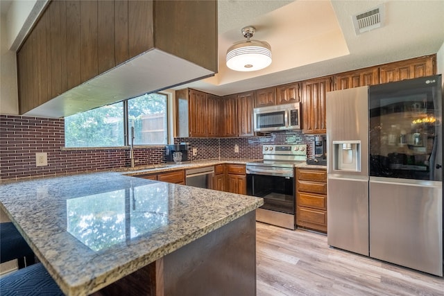 5705 Kingstree Ct, Arlington, TX 76017 - kitchen with appliances with stainless steel finishes, a peninsula, light stone countertops, and backsplash