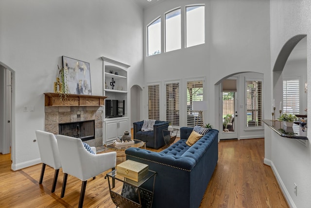 2248 Forest Hollow Park, Dallas, TX 75228 - living room with arched walkways, a fireplace, light wood finished floors, built in shelves, and a high ceiling