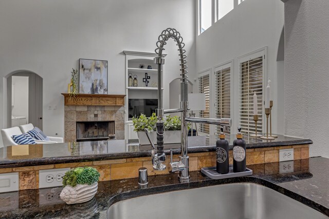 2248 Forest Hollow Park, Dallas, TX 75228 - kitchen with a towering ceiling, arched walkways, dark stone countertops, and a tile fireplace
