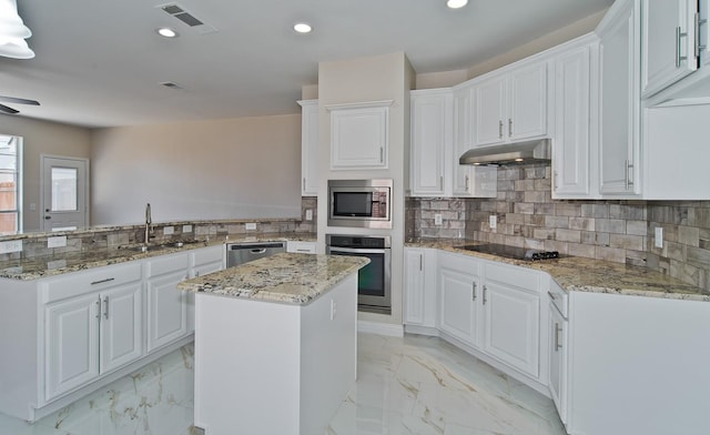 2505 Hunters Run Dr, Plano, TX 75025 - kitchen with appliances with stainless steel finishes, under cabinet range hood, a peninsula, light marble finish floors, and white cabinets