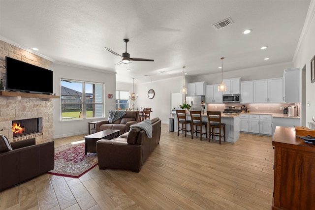 6105 Parma Ln, Temple, TX 76502 - living area with a ceiling fan, a stone fireplace, crown molding, light wood finished floors, and recessed lighting
