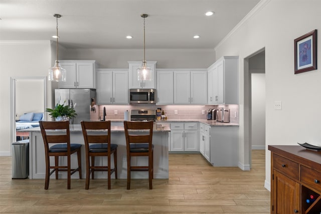 6105 Parma Ln, Temple, TX 76502 - kitchen featuring stainless steel appliances, a kitchen island with sink, backsplash, white cabinets, and light wood-type flooring