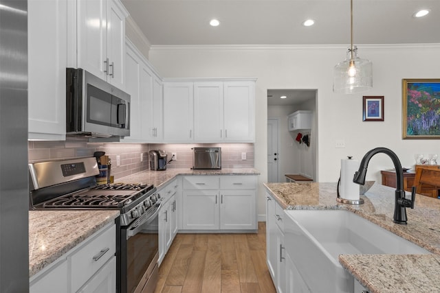 6105 Parma Ln, Temple, TX 76502 - kitchen with stainless steel appliances, light wood-style flooring, ornamental molding, white cabinets, and tasteful backsplash