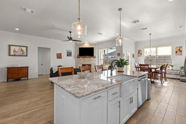 6105 Parma Ln, Temple, TX 76502 - kitchen with a stone fireplace, healthy amount of natural light, an island with sink, ornamental molding, and a ceiling fan