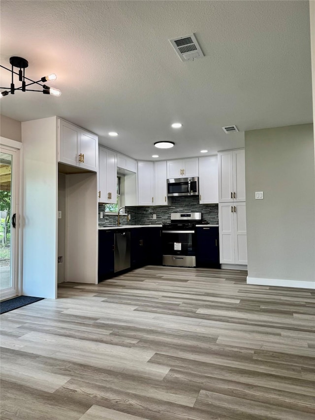 3633 Flamingo Way, Mesquite, TX 75150 - kitchen with appliances with stainless steel finishes, white cabinetry, backsplash, light wood finished floors, and recessed lighting