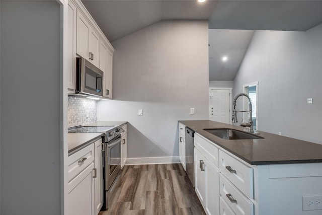 606 E 12th St, Bonham, TX 75418 - kitchen with appliances with stainless steel finishes, vaulted ceiling, a peninsula, dark countertops, and decorative backsplash