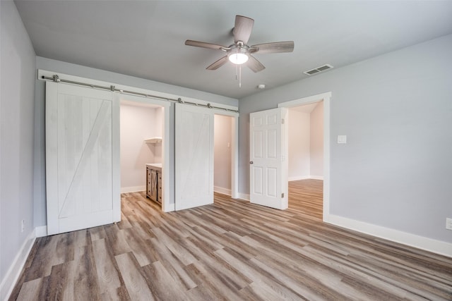 606 E 12th St, Bonham, TX 75418 - unfurnished bedroom with a barn door, wood finished floors, and ceiling fan
