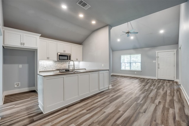 606 E 12th St, Bonham, TX 75418 - kitchen featuring stainless steel microwave, open floor plan, a ceiling fan, tasteful backsplash, and white cabinetry