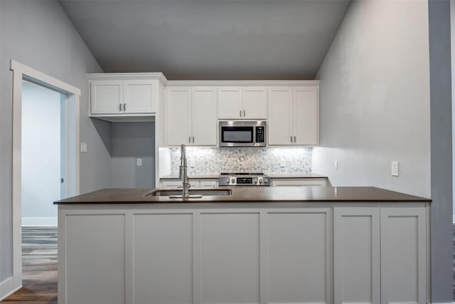 606 E 12th St, Bonham, TX 75418 - kitchen featuring appliances with stainless steel finishes, dark countertops, tasteful backsplash, and white cabinets