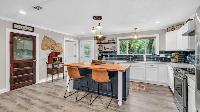 307 Bryan St, Weatherford, TX 76086 - kitchen with butcher block counters, stainless steel electric stove, a breakfast bar area, white cabinets, and a center island