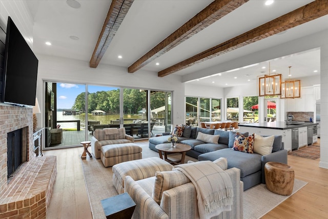 548 Winding Ln, Mount Vernon, TX 75457 - living room featuring beam ceiling, a chandelier, healthy amount of natural light, a brick fireplace, and light wood-style flooring