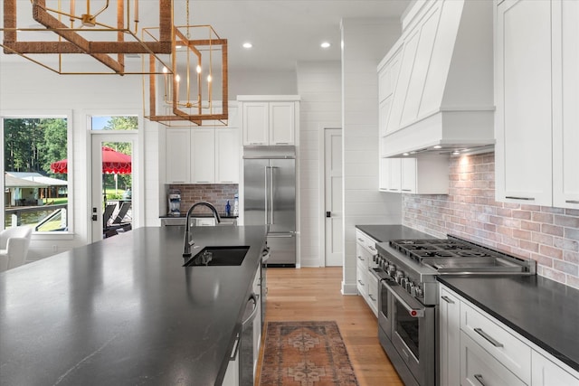 548 Winding Ln, Mount Vernon, TX 75457 - kitchen featuring high end appliances, custom range hood, dark countertops, light wood finished floors, and white cabinets