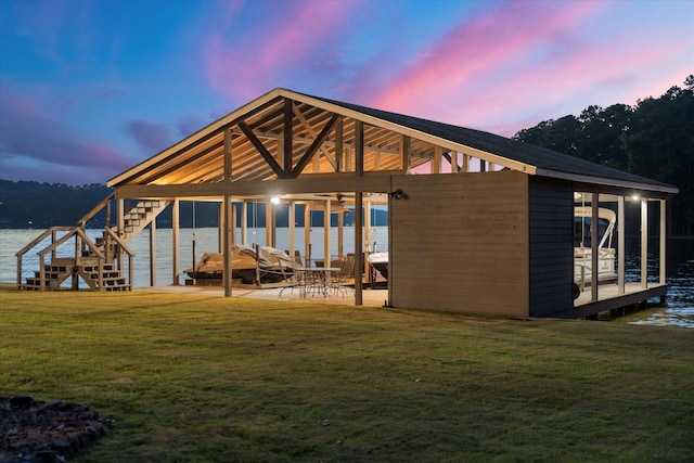 548 Winding Ln, Mount Vernon, TX 75457 - back of property at dusk with a lawn, a patio area, and a water view