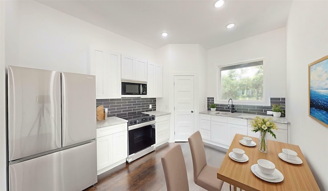 108 Frierson St, Waxahachie, TX 75165 - kitchen featuring appliances with stainless steel finishes, tasteful backsplash, white cabinetry, dark wood-style floors, and recessed lighting