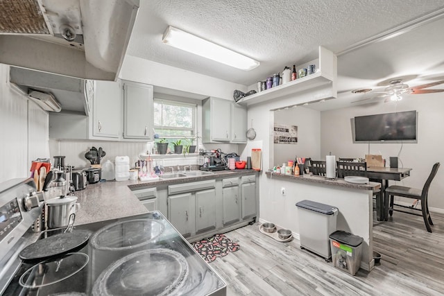 1106 Sunnyvale Dr, Arlington, TX 76010 - kitchen with light wood-style flooring, a ceiling fan, a peninsula, extractor fan, and a textured ceiling