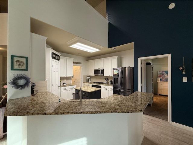 12763 Cardinal Creek Dr, Frisco, TX 75033 - kitchen with appliances with stainless steel finishes, a peninsula, white cabinets, and light wood-type flooring