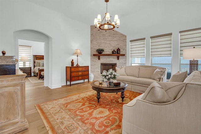 7432 Wispy Willow Ln, Little Elm, TX 76227 - living room featuring light wood finished floors, a stone fireplace, a chandelier, and vaulted ceiling