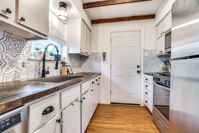 3323 Wise Dr, Mesquite, TX 75150 - kitchen with stainless steel appliances, dark countertops, light wood finished floors, decorative backsplash, and white cabinetry