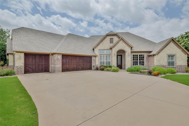 1306 Prestwick Ct, Granbury, TX 76048 - french country inspired facade featuring brick siding, a garage, concrete driveway, and roof with shingles
