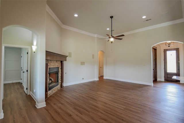1306 Prestwick Ct, Granbury, TX 76048 - unfurnished living room featuring arched walkways, a ceiling fan, wood finished floors, crown molding, and a stone fireplace