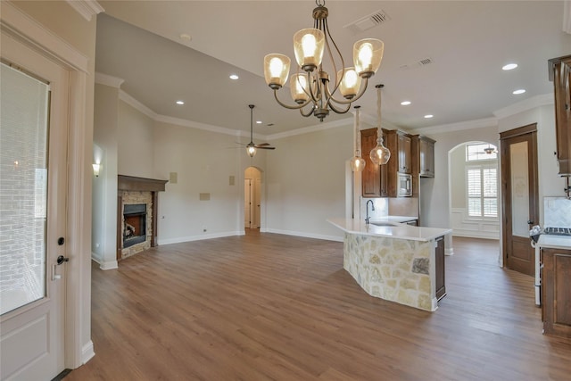 1306 Prestwick Ct, Granbury, TX 76048 - kitchen with arched walkways, wood finished floors, a ceiling fan, a fireplace, and a chandelier