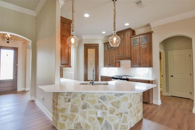 1306 Prestwick Ct, Granbury, TX 76048 - kitchen with arched walkways, gas stove, light countertops, glass insert cabinets, and light wood-style flooring