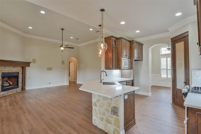 1306 Prestwick Ct, Granbury, TX 76048 - kitchen with arched walkways, stainless steel microwave, light countertops, a peninsula, and light wood finished floors