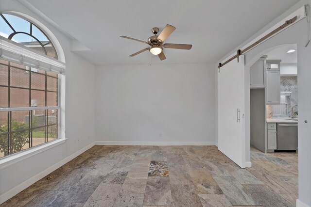 4418 Spring Garden Dr, Arlington, TX 76016 - empty room with a barn door, light stone finish flooring, ceiling fan, and arched walkways