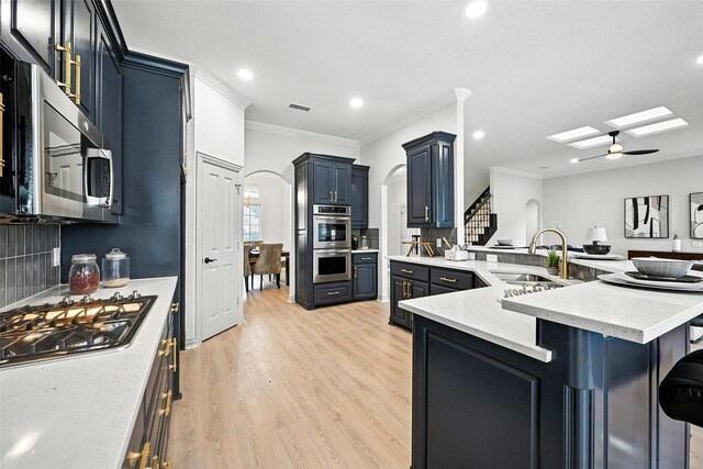 901 Bluebird Ct, Burleson, TX 76028 - kitchen featuring stainless steel appliances, arched walkways, light wood finished floors, a breakfast bar area, and a peninsula