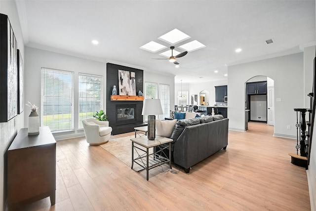 901 Bluebird Ct, Burleson, TX 76028 - living room with light wood-type flooring, a skylight, healthy amount of natural light, arched walkways, and recessed lighting