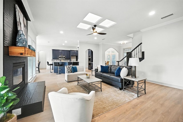 901 Bluebird Ct, Burleson, TX 76028 - living room featuring arched walkways, a skylight, crown molding, a fireplace, and recessed lighting