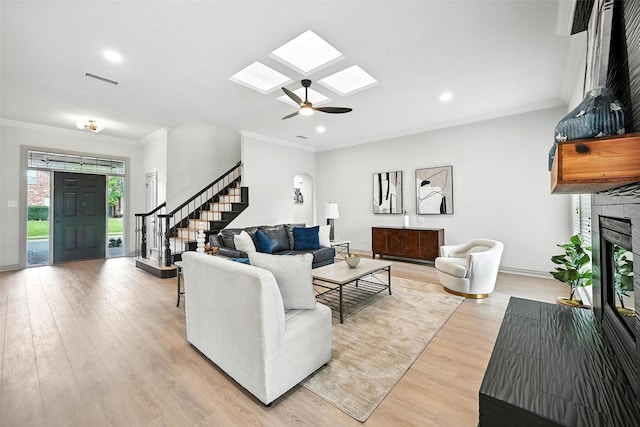 901 Bluebird Ct, Burleson, TX 76028 - living area with stairway, a skylight, ornamental molding, a fireplace with raised hearth, and light wood finished floors