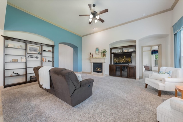306 Spruce Trl, Forney, TX 75126 - living room featuring arched walkways, carpet flooring, ceiling fan, ornamental molding, and a warm lit fireplace