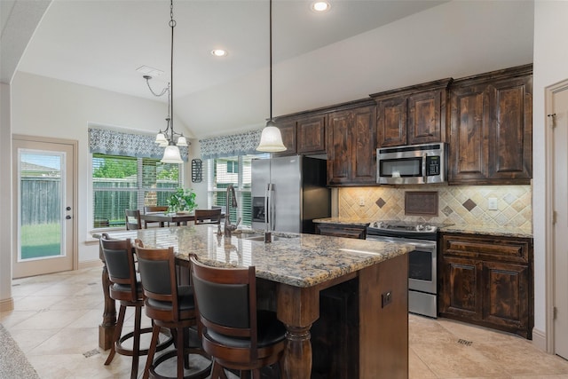 306 Spruce Trl, Forney, TX 75126 - kitchen featuring stainless steel appliances, tasteful backsplash, light stone countertops, a kitchen island with sink, and dark brown cabinets