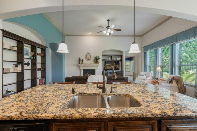 306 Spruce Trl, Forney, TX 75126 - kitchen featuring open floor plan, ornamental molding, a ceiling fan, a fireplace, and light stone countertops