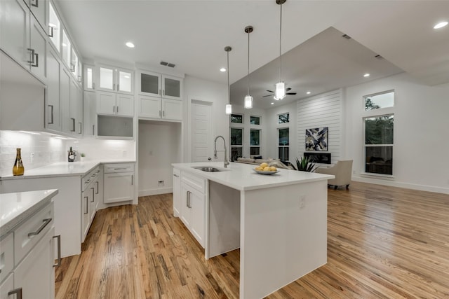 1403 Pueblo St, Dallas, TX 75212 - kitchen featuring light wood finished floors, a ceiling fan, open floor plan, glass insert cabinets, and backsplash