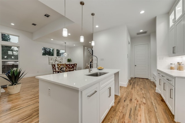 1403 Pueblo St, Dallas, TX 75212 - kitchen featuring light wood-type flooring, recessed lighting, white cabinets, decorative light fixtures, and an island with sink
