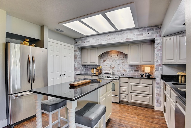 351 Marion Rd, Venus, TX 76084 - kitchen with stainless steel appliances, dark countertops, a breakfast bar, decorative backsplash, and wood finished floors