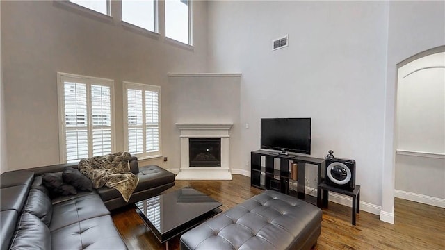 1320 Ponca St, Carrollton, TX 75010 - living area with healthy amount of natural light, a towering ceiling, wood finished floors, and arched walkways