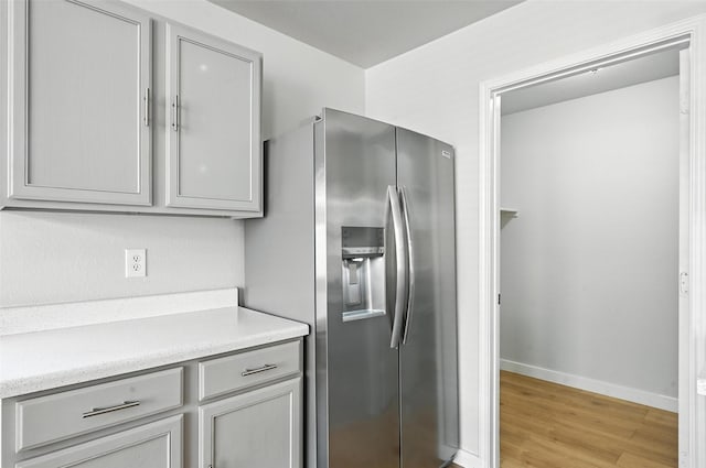 1908 Ramada Trl, Fort Worth, TX 76247 - kitchen with stainless steel refrigerator with ice dispenser, gray cabinetry, light countertops, and light wood-style floors
