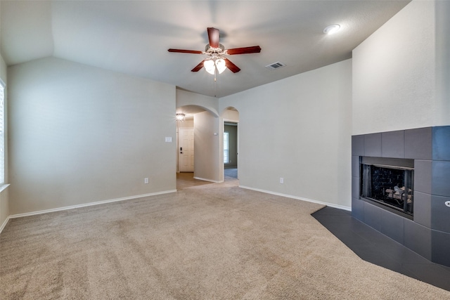 9032 Eagle Dr, Providence Village, TX 76227 - unfurnished living room featuring a tiled fireplace, ceiling fan, arched walkways, carpet flooring, and vaulted ceiling