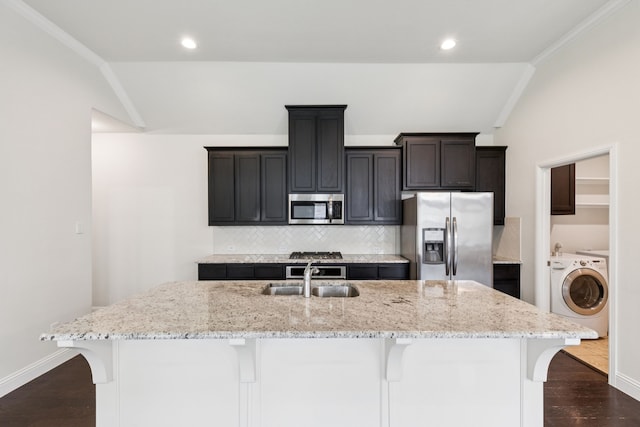 913 Parkside Dr, Argyle, TX 76226 - kitchen with stainless steel appliances, washer / dryer, vaulted ceiling, an island with sink, and a kitchen breakfast bar