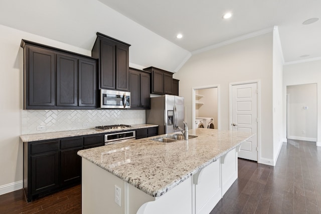 913 Parkside Dr, Argyle, TX 76226 - kitchen featuring appliances with stainless steel finishes, washing machine and clothes dryer, an island with sink, backsplash, and dark wood finished floors