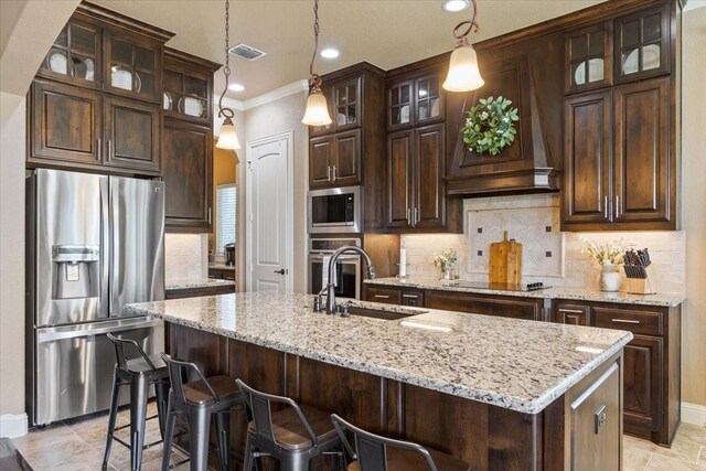 2213 Therese Dr, Waco, TX 76712 - kitchen featuring stainless steel appliances, dark brown cabinetry, a kitchen island with sink, crown molding, and hanging light fixtures
