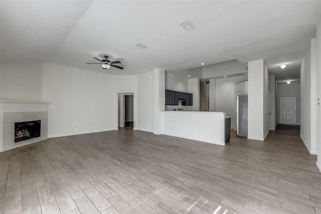 6414 Seaford Rd, Arlington, TX 76001 - unfurnished living room with ceiling fan, light wood-type flooring, a fireplace, a textured ceiling, and vaulted ceiling