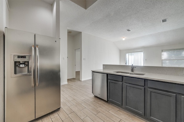 6414 Seaford Rd, Arlington, TX 76001 - kitchen featuring appliances with stainless steel finishes, vaulted ceiling, gray cabinets, a textured ceiling, and light wood-type flooring