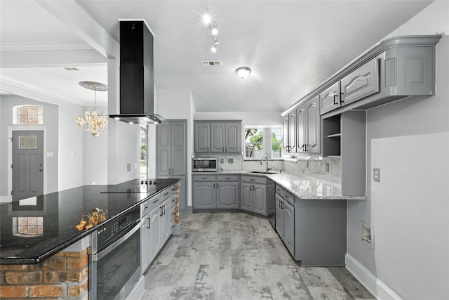 8301 Concord Dr, Rowlett, TX 75089 - kitchen with gray cabinets, wall chimney exhaust hood, appliances with stainless steel finishes, and a chandelier
