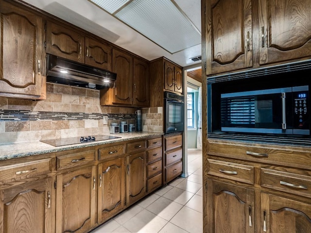 713 Bordner Dr, Lancaster, TX 75146 - kitchen featuring black appliances, under cabinet range hood, light tile patterned flooring, tasteful backsplash, and light stone countertops