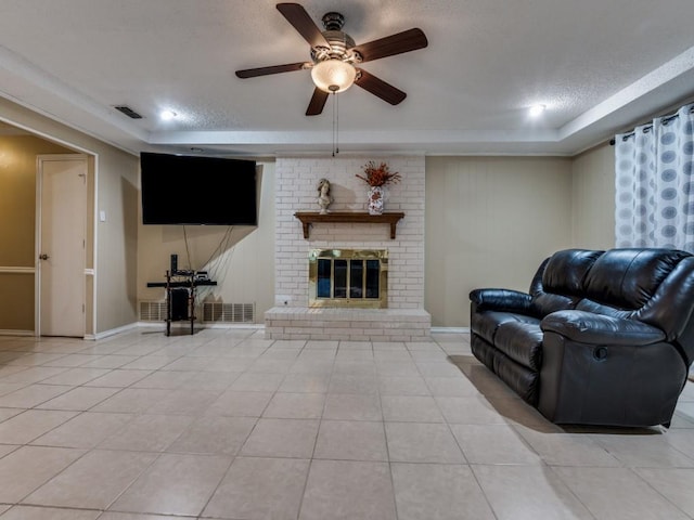 713 Bordner Dr, Lancaster, TX 75146 - living area with a textured ceiling, light tile patterned flooring, ceiling fan, a fireplace, and a raised ceiling
