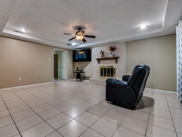 713 Bordner Dr, Lancaster, TX 75146 - living room featuring a raised ceiling, a textured ceiling, ceiling fan, light tile patterned floors, and a fireplace
